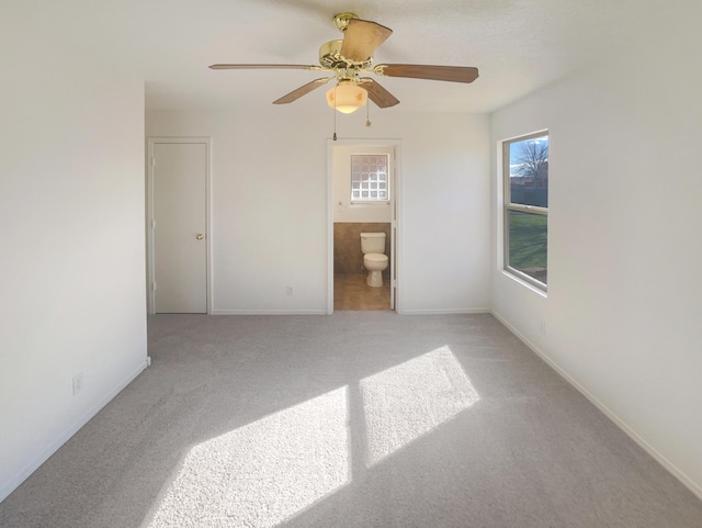 empty room featuring light carpet, a healthy amount of sunlight, baseboards, and a ceiling fan