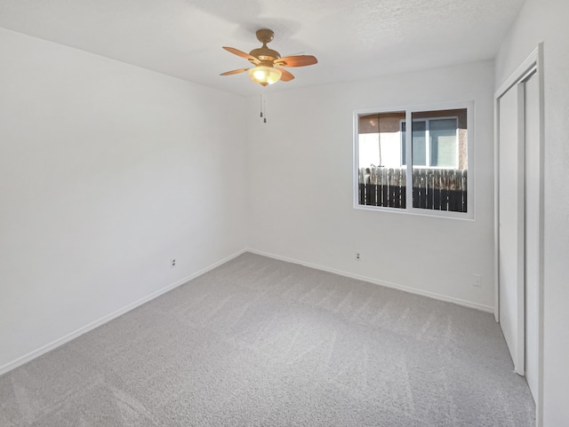 empty room with ceiling fan, a textured ceiling, baseboards, and carpet