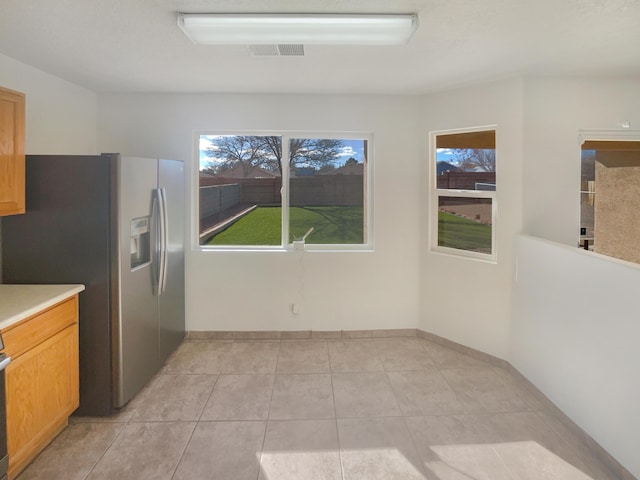 kitchen with light countertops, light tile patterned floors, visible vents, and stainless steel refrigerator with ice dispenser