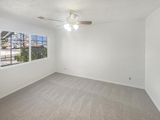 carpeted empty room with visible vents, baseboards, a textured ceiling, and ceiling fan