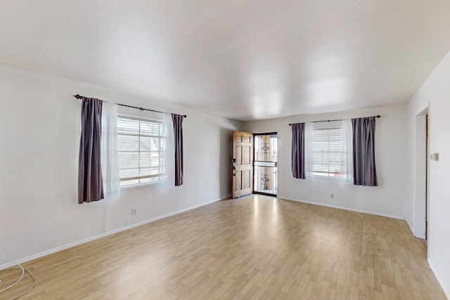 spare room featuring baseboards and light wood-type flooring