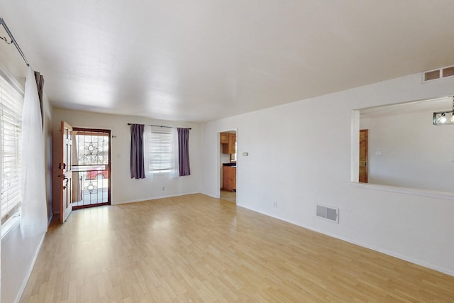 unfurnished room featuring visible vents, baseboards, and light wood finished floors