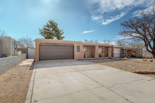 adobe home with stucco siding, driveway, a garage, and fence