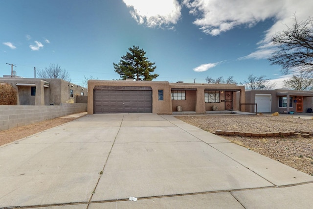 adobe home with a garage, concrete driveway, and stucco siding