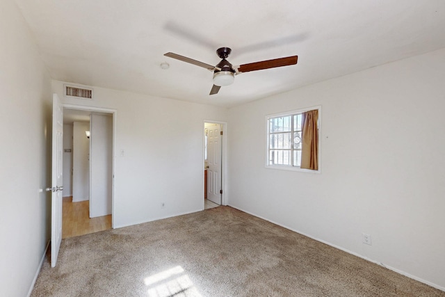 unfurnished bedroom featuring visible vents, light colored carpet, and a ceiling fan