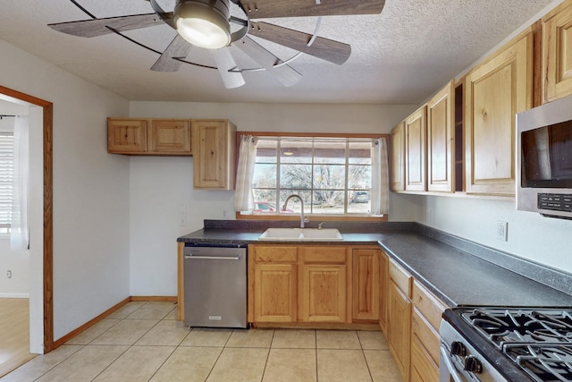 kitchen featuring a sink, dark countertops, appliances with stainless steel finishes, and light tile patterned flooring