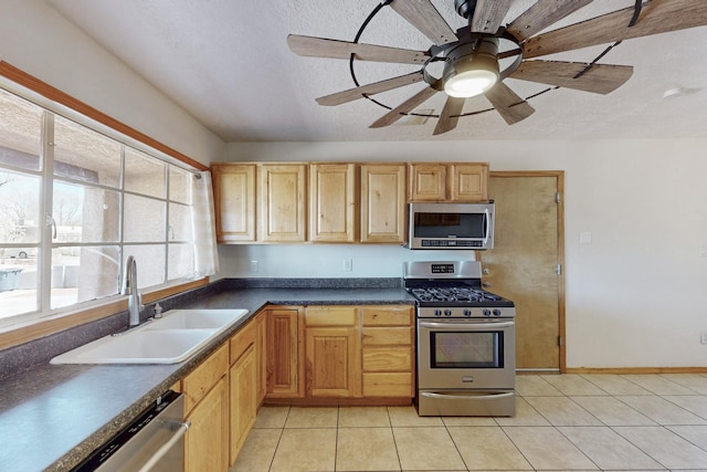 kitchen featuring dark countertops, light tile patterned floors, stainless steel appliances, a textured ceiling, and a sink