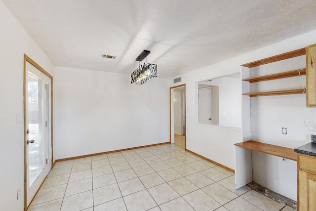 unfurnished dining area with light tile patterned floors, visible vents, baseboards, and a textured ceiling