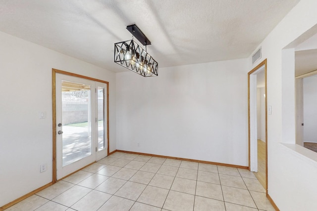 unfurnished dining area featuring light tile patterned floors, visible vents, baseboards, and a textured ceiling