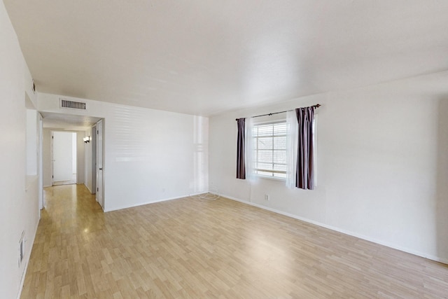 empty room with light wood-style flooring, baseboards, and visible vents