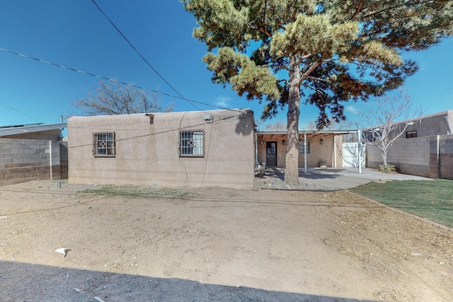 rear view of house with stucco siding and fence