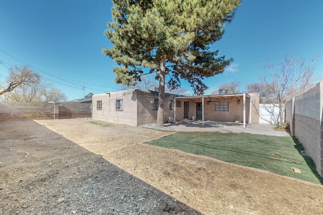 back of house with stucco siding, a patio, and a fenced backyard