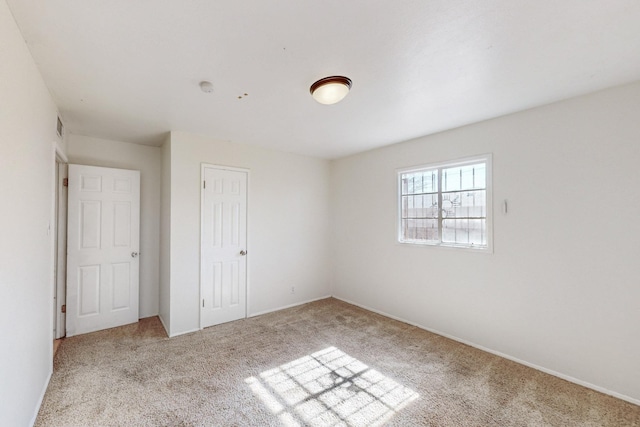 unfurnished bedroom with a closet, carpet floors, and visible vents