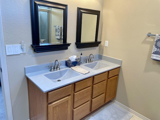 full bathroom featuring a sink, baseboards, double vanity, and tile patterned floors