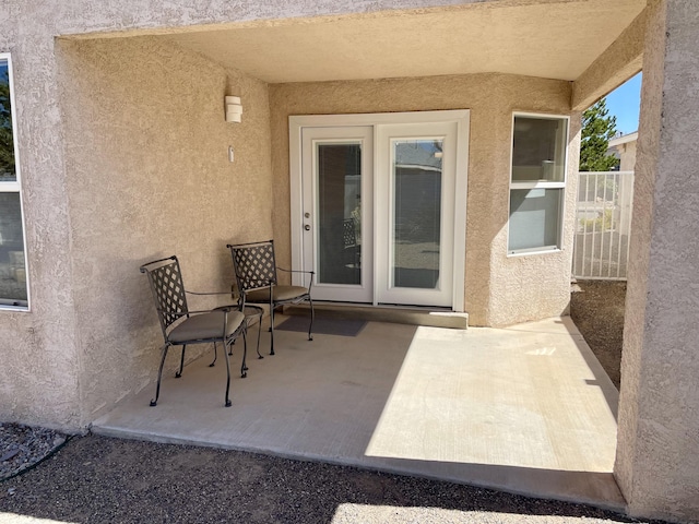 view of exterior entry featuring stucco siding and a patio