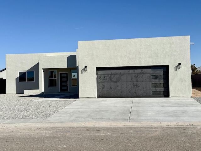 contemporary house with stucco siding, an attached garage, and driveway