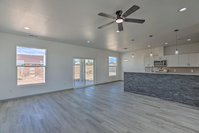unfurnished living room featuring light wood-type flooring, a ceiling fan, visible vents, and recessed lighting