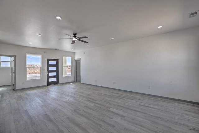 empty room with a wealth of natural light, wood finished floors, and visible vents