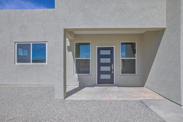 property entrance with stucco siding and a patio