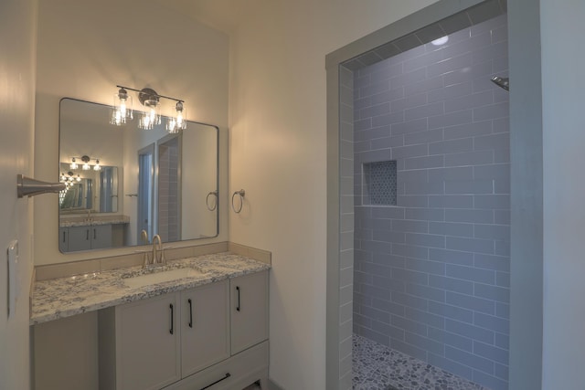 bathroom with a tile shower and vanity