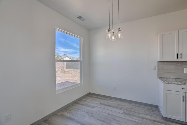 unfurnished dining area with baseboards, light wood-style flooring, and visible vents