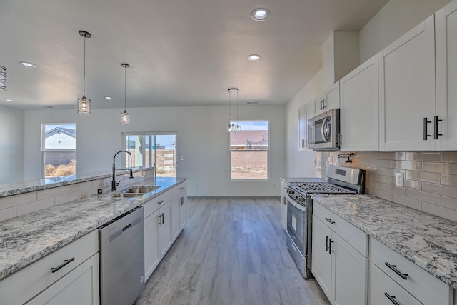 kitchen featuring light wood-style floors, white cabinetry, stainless steel appliances, and a sink