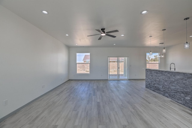 unfurnished living room with a ceiling fan, a sink, light wood finished floors, baseboards, and recessed lighting
