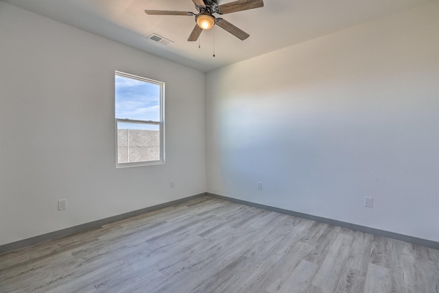 spare room with light wood-type flooring, visible vents, a ceiling fan, and baseboards