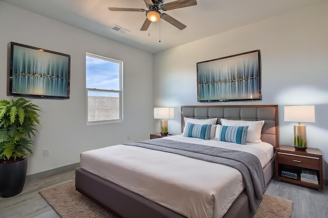 bedroom featuring baseboards, a ceiling fan, wood finished floors, and visible vents