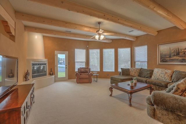 living area with carpet, visible vents, ceiling fan, beamed ceiling, and a large fireplace