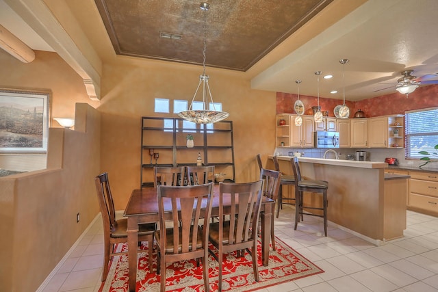 dining area with visible vents, a tray ceiling, light tile patterned floors, baseboards, and ceiling fan