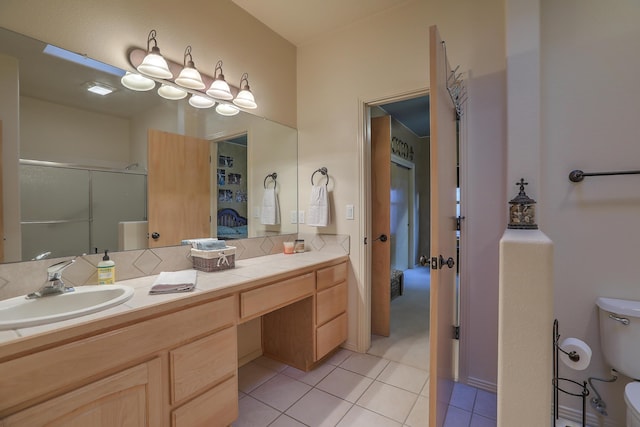 bathroom featuring tile patterned floors, toilet, vanity, and a shower with shower door