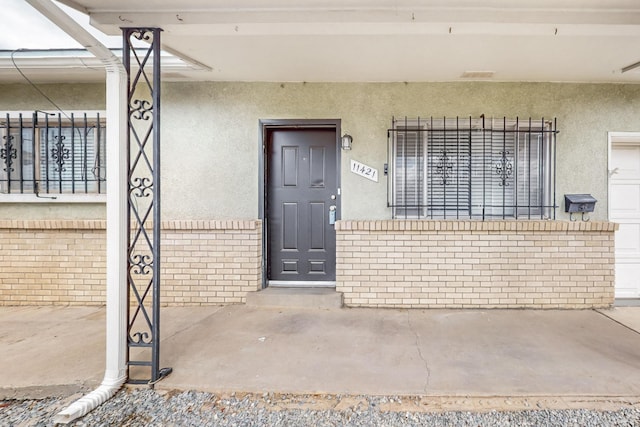 doorway to property featuring stucco siding and brick siding