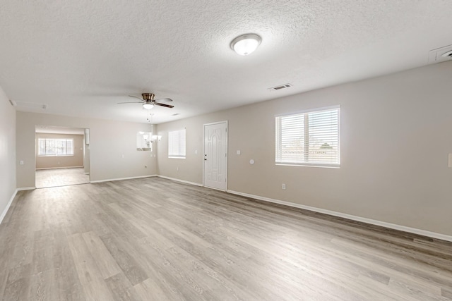 unfurnished living room featuring baseboards, a textured ceiling, light wood-style flooring, and ceiling fan with notable chandelier