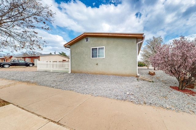 view of property exterior with stucco siding and fence