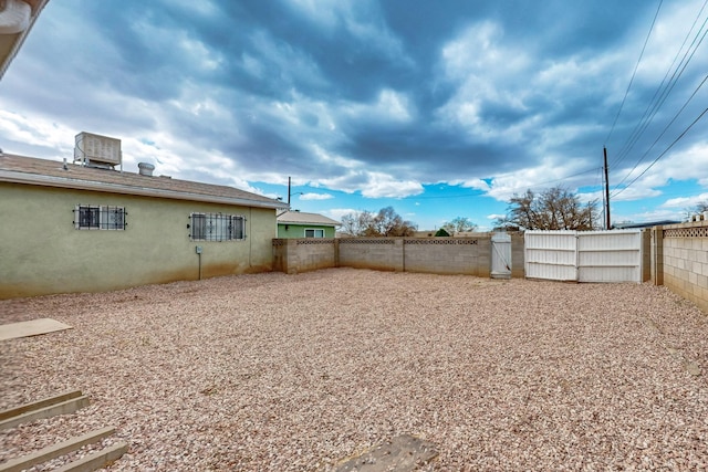 view of yard featuring central air condition unit, a fenced backyard, and a gate