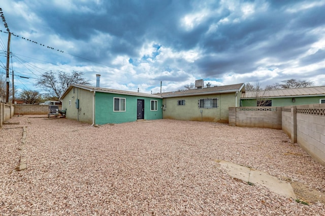 back of house with a fenced backyard and stucco siding