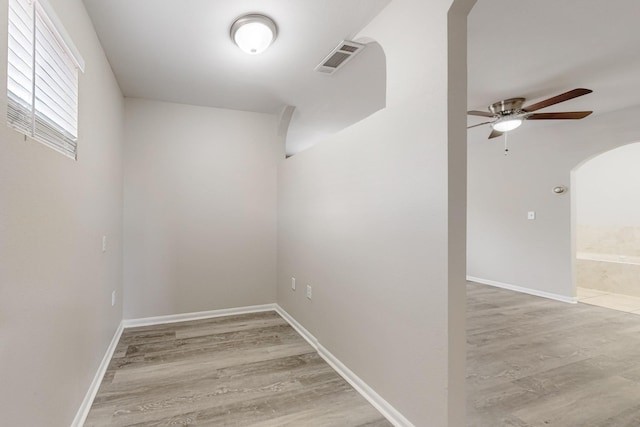 unfurnished room featuring arched walkways, visible vents, ceiling fan, and light wood-style floors