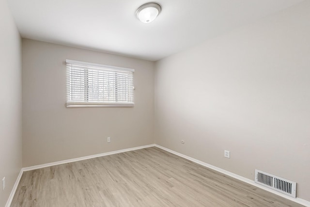 unfurnished room featuring wood finished floors, visible vents, and baseboards