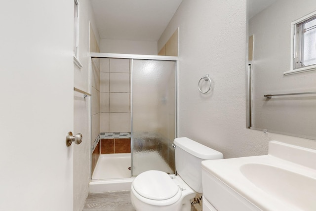 full bathroom with a stall shower, toilet, vanity, and a textured wall