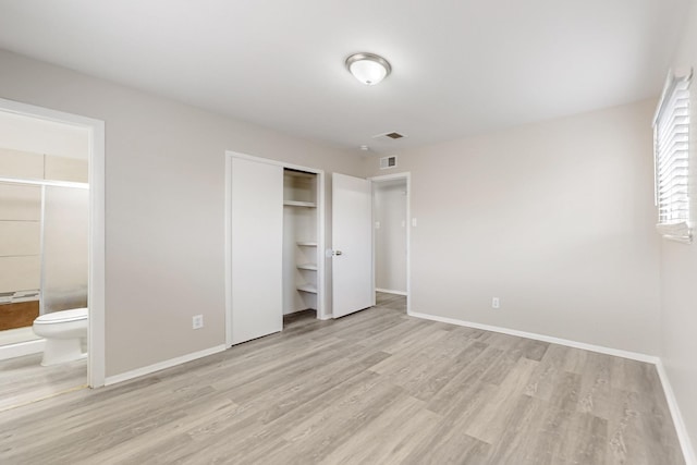 unfurnished bedroom featuring visible vents, a closet, connected bathroom, light wood finished floors, and baseboards