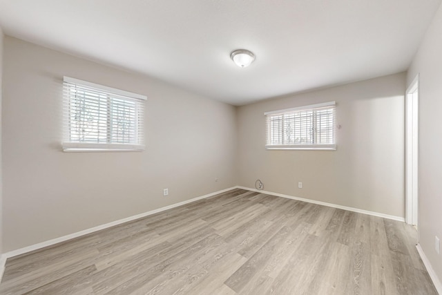 unfurnished room featuring plenty of natural light, baseboards, and light wood-style floors