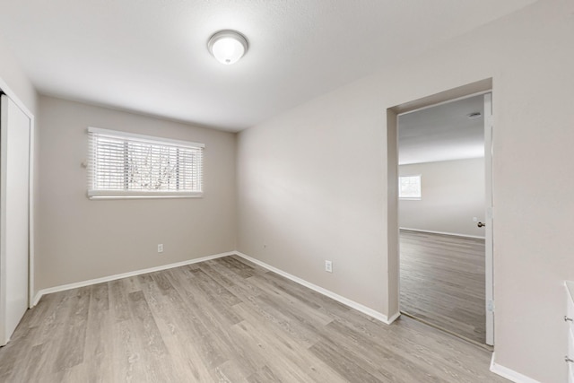 unfurnished room with baseboards and light wood-style floors