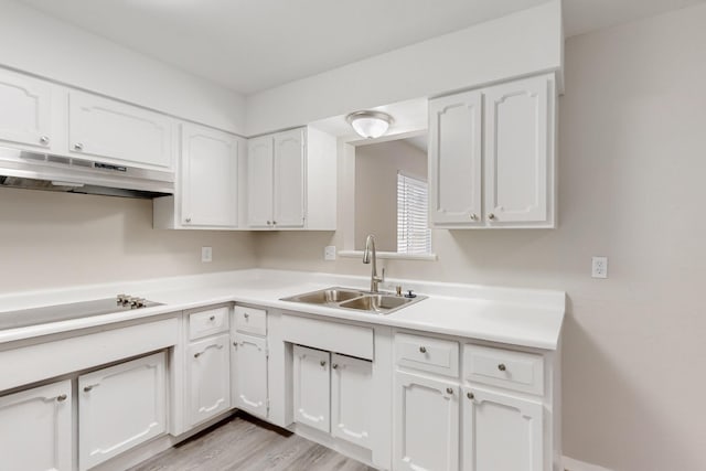 kitchen featuring under cabinet range hood, light countertops, electric stovetop, white cabinets, and a sink