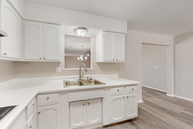 kitchen featuring white cabinets, light countertops, light wood-style flooring, and a sink