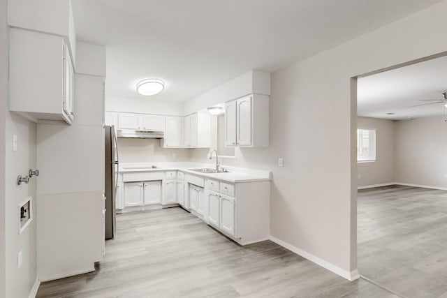 kitchen featuring white cabinetry, freestanding refrigerator, a ceiling fan, and a sink