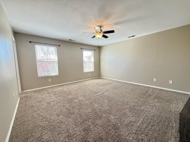 carpeted spare room featuring visible vents, baseboards, a textured ceiling, and ceiling fan