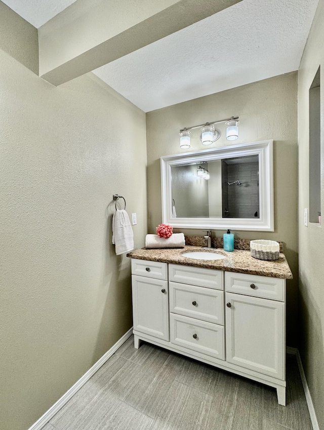 bathroom featuring vanity, a shower, and baseboards