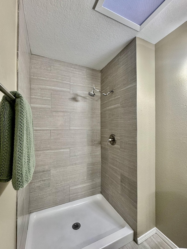 bathroom with visible vents, baseboards, a textured ceiling, and a tile shower