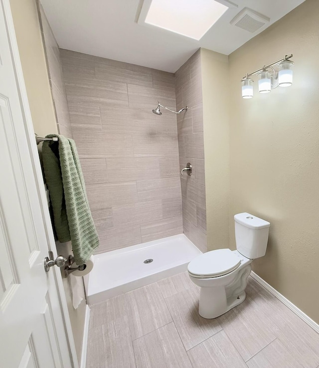 full bath featuring a tile shower, visible vents, toilet, and baseboards